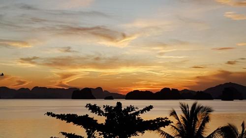 a sunset over the water with mountains in the background at Hillhouse - Koh Yao Noi in Ko Yao Noi