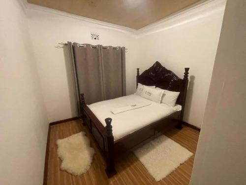 Dormitorio pequeño con cama con sábanas y almohadas blancas en SERENE GUEST HOUSE en Eldoret