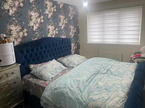 a bedroom with a bed with a blue headboard and flowers at 3-Bedrooms House in Thornliebank Glasgow in Mansewood