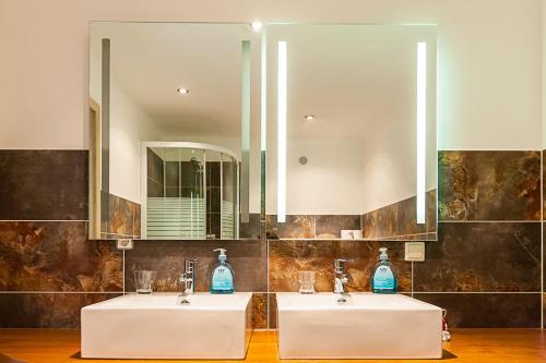 two sinks in a bathroom with two mirrors at Gasthof Post in Sankt Gallen