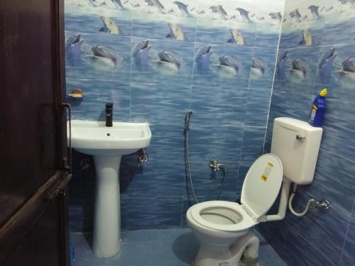 ein Badezimmer mit einem WC und einem Waschbecken mit Delfinen an der Wand in der Unterkunft KAUSHALYADHAM MUNSYARI in Munsyari