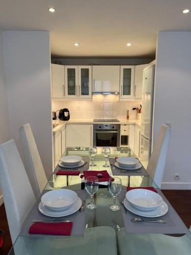 a kitchen with a table with plates and wine glasses at bel appartement chic et cosy 78100 in Saint-Germain-en-Laye