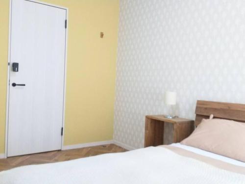 - une chambre avec un lit blanc et une porte blanche dans l'établissement プライベートサウナがあるGuestHouseレビッキ【水上駅】より徒歩10分【水上IC】より車7分, à Minakami