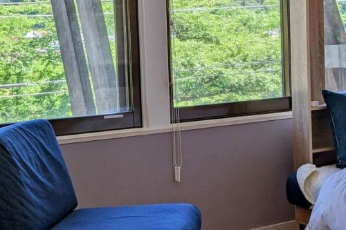 a room with a blue chair and two windows at プライベートサウナがあるGuestHouseレビッキ【水上駅】より徒歩10分【水上IC】より車7分 in Minakami