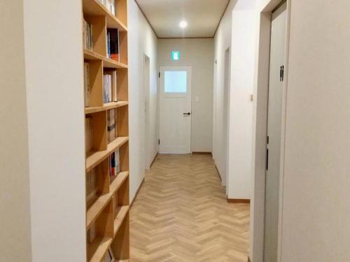 a hallway with bookshelves and a white door at プライベートサウナがあるGuestHouseレビッキ【水上駅】より徒歩10分【水上IC】より車7分 in Minakami