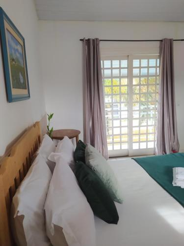 een slaapkamer met een bed met witte kussens en een raam bij Recanto do Turista in Chapada dos Guimarães