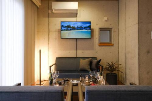 a living room with a table and a tv on the wall at 琉球モダンスタイルの那覇の閑静な隠れ家 駅まで徒歩圏内の好立地 1階 in Kume