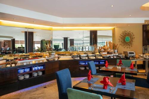 a restaurant with tables and chairs and a buffet at Hotel Ciputra Semarang managed by Swiss-Belhotel International in Semarang