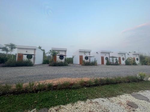 a row of white modular houses on a gravel road at Muji House Resort in Non Sang