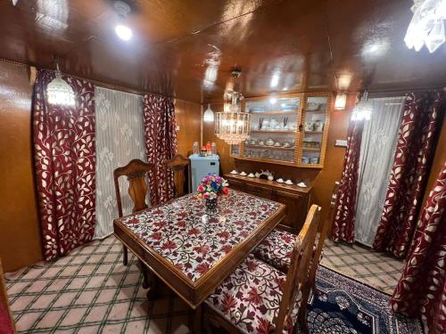 a dining room with a table and chairs and curtains at Houseboat wild rose in Srinagar