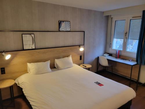 a bedroom with a large white bed and a desk at ibis Chateauroux in Châteauroux