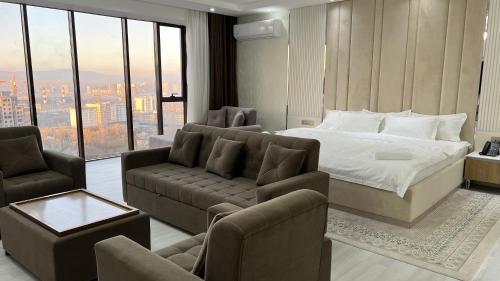 a bedroom with a bed and a couch and chairs at Hotel Panorama in Dushanbe