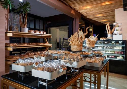 a buffet with many different types of bread and pastries at Hotel Ciputra Semarang managed by Swiss-Belhotel International in Semarang