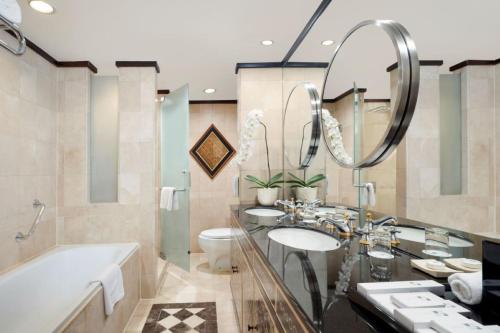 a bathroom with two sinks and a tub and a large mirror at Hotel Ciputra Semarang managed by Swiss-Belhotel International in Semarang