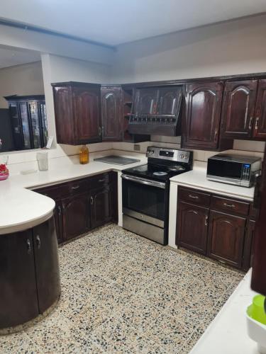 uma cozinha com armários de madeira e um forno com placa de fogão em Familiar y Acogedor em San Pedro Sula