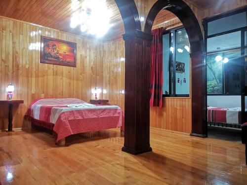 ein Schlafzimmer mit einem Bett in einem Zimmer mit Holzwänden in der Unterkunft Casa Judá in San Cristóbal de las Casas