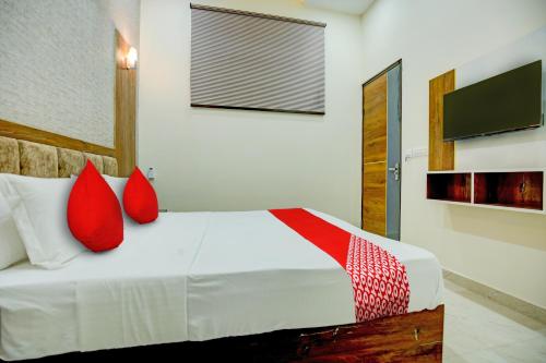 um quarto com uma cama com almofadas vermelhas e uma televisão em Super OYO Flagship Hotel Elista em Zirakpur