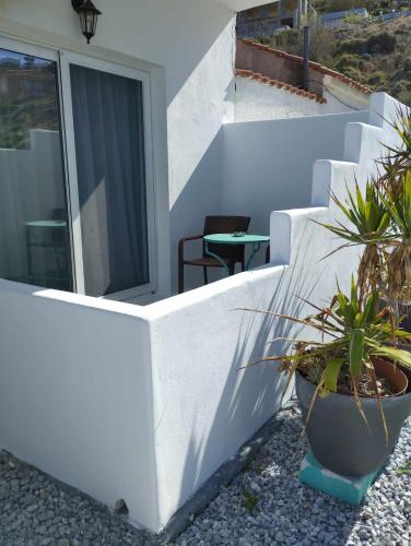 a white wall with potted plants on a patio at Soultana’s house in Mourteri