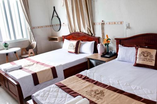 um quarto de hotel com duas camas e uma mesa em Khách Sạn Tuyết Linh Lý Sơn em Quang Ngai
