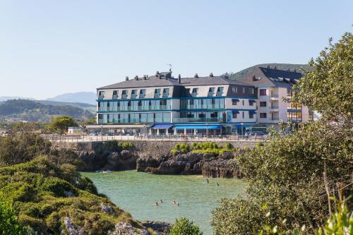 un hôtel sur la plage avec des gens dans l'eau dans l'établissement Hotel Astuy, à Isla