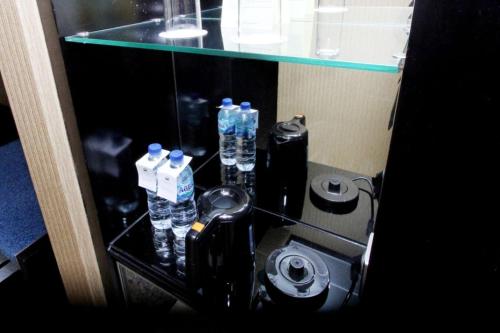a glass shelf with bottles of water in a bathroom at Hotel Ciputra Semarang managed by Swiss-Belhotel International in Semarang