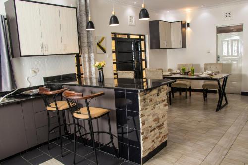 a kitchen and dining room with a counter and stools at Cacecy Luxury Homes 2 -Bedroom in Bungoma