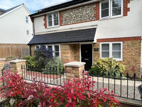 a house with a black fence and red flowers at Luxurious Two-Bedroom Suite with Patio & EV power in Greenhithe