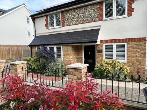 a house with a black fence and red flowers at Two-Bedroom Cosy Country Lodge with Private Patio in Greenhithe