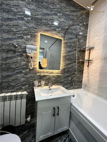 La salle de bains est pourvue d'un lavabo, d'une baignoire et d'un miroir. dans l'établissement Comfortable 2-roomed apartment Ozod Apartments, à Samarcande