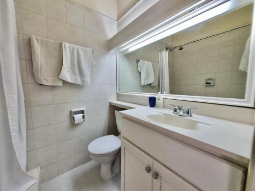 La salle de bains est pourvue d'un lavabo, de toilettes et d'un miroir. dans l'établissement 12 Foursquare Rockley Golf & Country Club, à Bridgetown