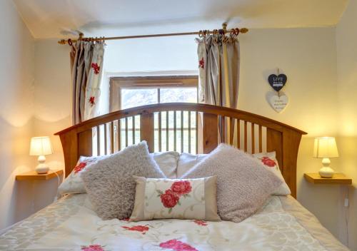 a bedroom with a bed with pillows and a window at Mynydd Annedd Cottage in Beddgelert