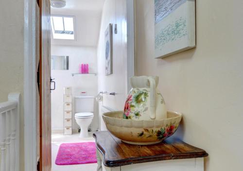 a bathroom with a bowl on a table with a toilet at Mynydd Annedd Cottage in Beddgelert