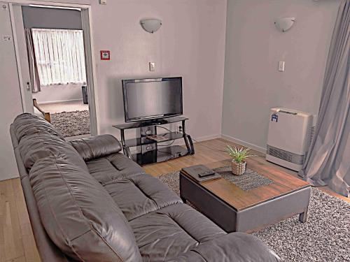 a living room with a couch and a flat screen tv at Newlands Court Motel in Wellington