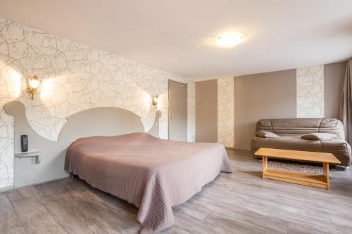 a hotel room with a bed and a couch at Logis SPA Hotel Restaurant De La Poste in Tence