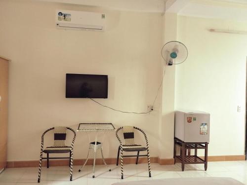 una camera con due sedie, un tavolo e una TV di Tuong Vy Hotel ad Ho Chi Minh