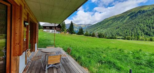 a wooden deck with a table and chairs on a house at Chalet Breithorn- Perfect for Holiday with Amazing View! in Obergesteln