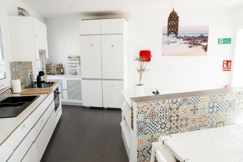 SurfersResidence Tarifa في تريفة: مطبخ بخزائن بيضاء وجدار من البلاط