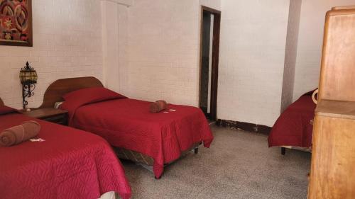 a room with two beds with red covers in it at Royal Palace Hostal in Panajachel