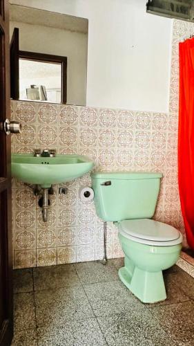 a bathroom with a green toilet and a sink at Royal Palace Hostal in Panajachel