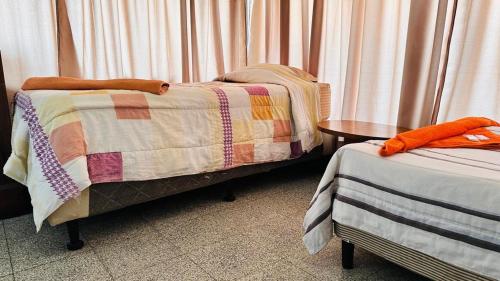 a room with two twin beds and a table at Royal Palace Hostal in Panajachel