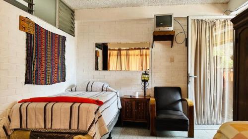 ein Schlafzimmer mit einem Bett, einem Stuhl und einem Spiegel in der Unterkunft Royal Palace Hostal in Panajachel