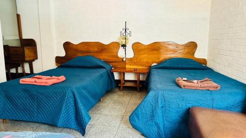 a bedroom with two beds with blue sheets and a table at Royal Palace Hostal in Panajachel