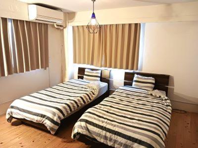 two beds sitting next to each other in a room at Guesthouse Banvina in Kagoshima