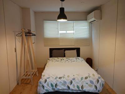 a bedroom with a bed in a room with a window at Guesthouse Banvina in Kagoshima