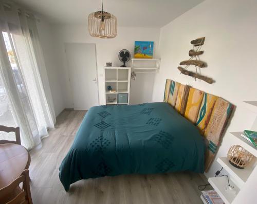 1 dormitorio con 1 cama con manta azul en La chambre de Séraphine, en Biscarrosse
