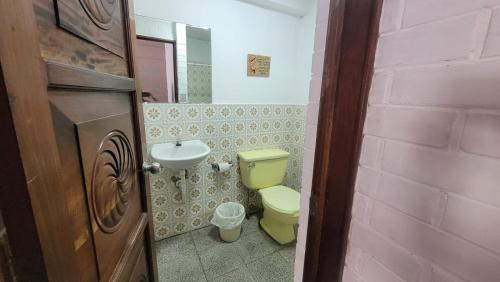 a bathroom with a yellow toilet and a sink at Royal Palace Hostal in Panajachel