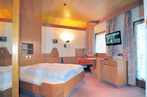 a bedroom with a large bed and a television at Pension Alpenhof in San Leonardo in Passiria