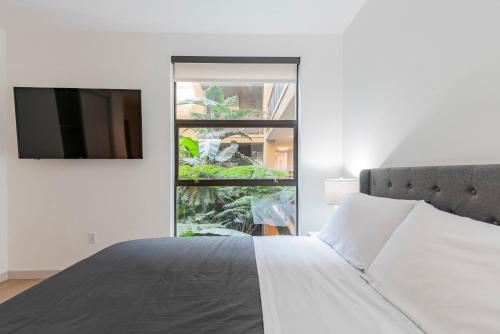 una camera bianca con un letto e una grande finestra di 2BR Hollywood Modern Luxury Condo a Los Angeles