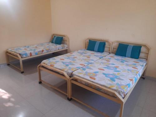 2 camas con almohadas azules en una habitación en Swami Sahvas Homestay, en Kudāl