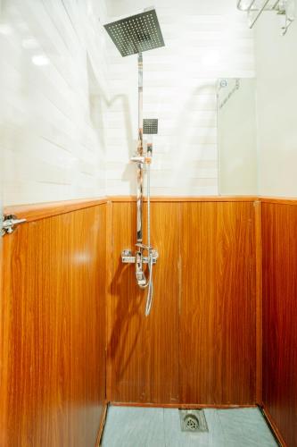 a shower in a room with a wooden wall at Wafami Hostel Ninh Binh in Ninh Binh